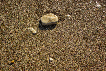 sea shore waterfront district of wet stones on sand background texture near weaves with empty space for copy or text 