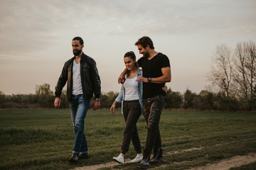 Couple walking with friend in nature and talking