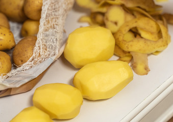 Womans hands with small kitchen knife. Potatoes peeling. Bag with unpeeled potatoes.