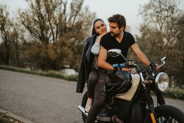 Fototapeta na wymiar Man riding motorcycle with girlfriend behind him smiling