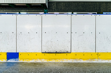 Hockey rink side boards with door and scratched and damaged surface
