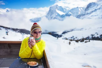 Rolgordijnen Wintersport Woman drinking coffee in mountains after ski.