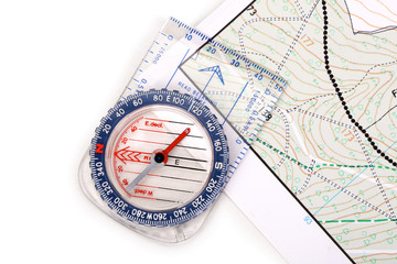 Modern plastic compass with scales and rulers on top of a detailed hiking map on white background, contains clipping path