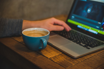 mans hand close up working on laptop with cup of coffee