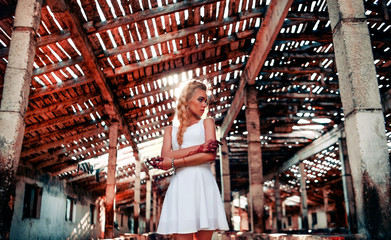 A girl in a white dress standing in a ruined house.  Hands in blood