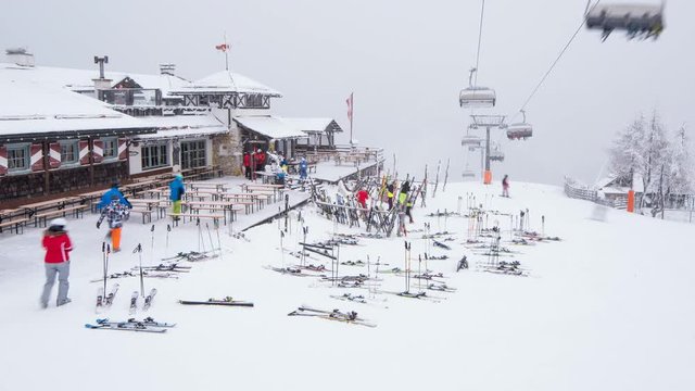 Time Lapse - Ski hut in a ski area with a moving chairlift, skier and falling snow - winter