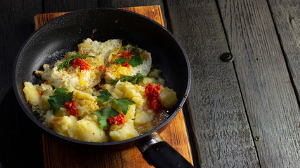 Homemade Fried Potatoes and Omelettes in a Frying Pan. On an old black wooden table