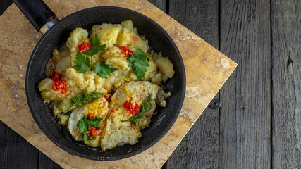 Homemade Fried Potatoes and Omelettes in a Frying Pan. On an old black wooden table