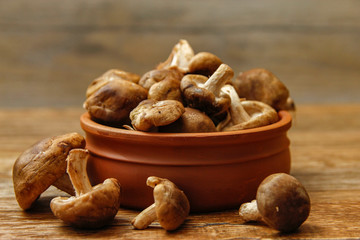 Fresh shiitake mushroom on wooden table, close-up photo in rustic ambient with low light