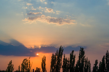 Landscape with dramatic light - beautiful golden sunset with saturated sky and clouds.