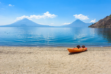 Paradise beach with chair and kayak at lake Atitlan, Panajachel - Relaxing and recreation at beach with vulcano landscape scenery in the highlands of Guatemala