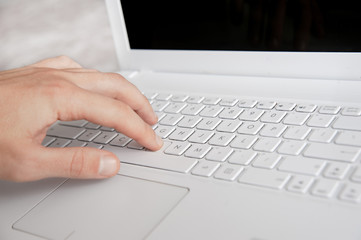 mans hand typing on white keyboard by fingers. white workspace