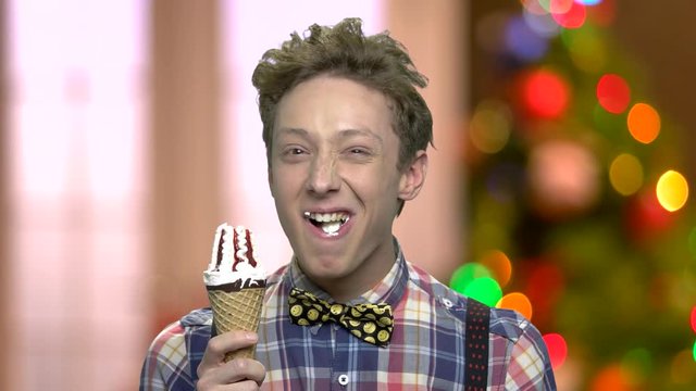 Funny teenage guy eating ice cream. Portrait of teen boy with ice cream cone. Abstract Christmas background.