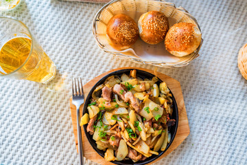 Roasted potato in frying pan with meat and green leek