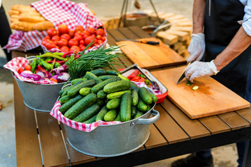 Chef slices fresh vegetables for salad in outdoor kitchen