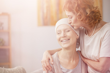 Bright photo of senior redhead woman kissing forehead of her happy cancer sick sister