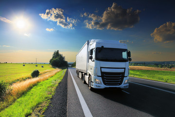 White truck driving through autumn landscape at sunset