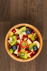 Fruit Salad in Wooden Bowl on Wooden Table, Top View Centered