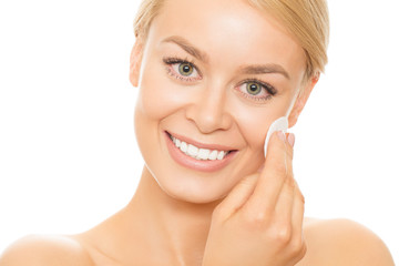 Studio close up of a gorgeous happy woman with healthy perfect skin cleansing her face with a cotton pad smiling to the camera isolated on white beauty cosmetology spa skincare freshness youth smooth