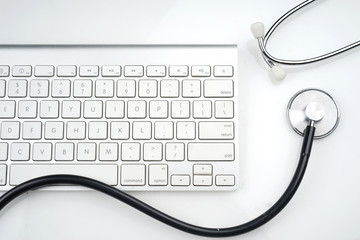 Adoption of technology in healthcare industry concept. Stethoscope and keyboard on white background. Flat lay or top view.  