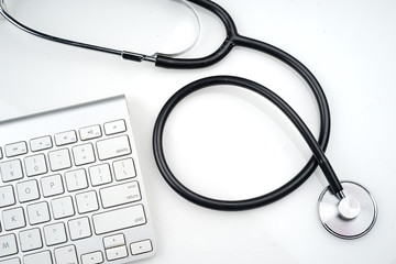 Adoption of technology in healthcare industry concept. Stethoscope and keyboard on white background. Flat lay or top view.  