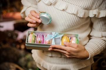 Girl holding a blue macaroon and box of many glittering toy bulbs of different colors