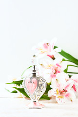 Luxurious perfume bottle with flowers on white background. Feminine beauty concept.
