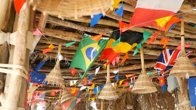 Decorative national flags of different countries hanging on strings in wooden tropical bungalow. Exotic rasta bar interior. Summer beach house on Koh Phangan island, Thailand.
