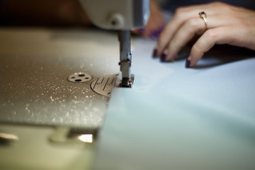 Workplace seamstress. Tailoring industry. Girl sews on the sewing machine. Factory clothing