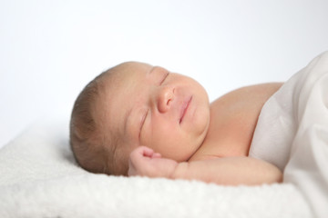 Fototapeta na wymiar Schlafendes Neugeborenes liegt auf einem Fell