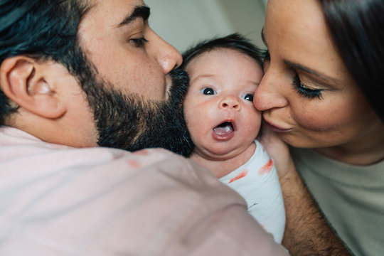 Parents kissing their newborn baby