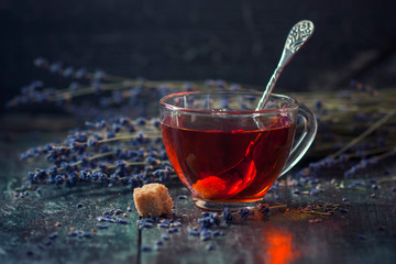 A cup of hot black tea with sugar and lavender on a dark wooden background. Breakfast concept.