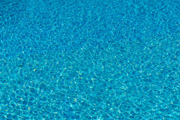 Fototapeta na wymiar Blue water in swimming pool background. Ripple Water in swimming pool with sun reflection. Blue swimming pool rippled water detail