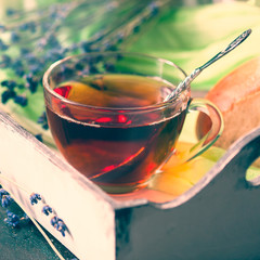 Wooden tray with cup of hot black tea with light breakfast.