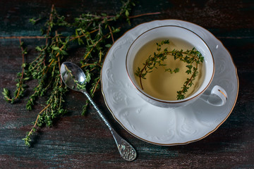 Cup of herbal tea with thyme on a wooden table