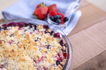 Close up on a homemade berry cobbler on a wood table, with space for text on the right
