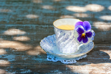 Obraz na płótnie Canvas Porcelain cup of tea on a wooden table in the garden. Summer party