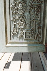 Retro style wooden door with flower sculpture with light and shadow from the sun