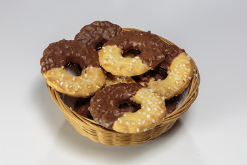 Basket with delicious ring-shaped chocolate chip cookies on a white background closeup.