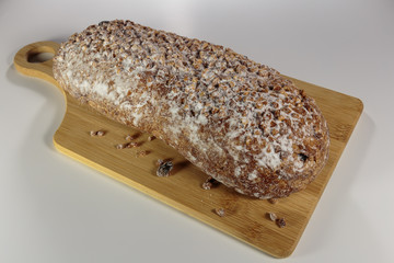 Pound cake with walnuts and raisins on a cutting board. Sprinkled by powdered sugar and crushed walnuts.