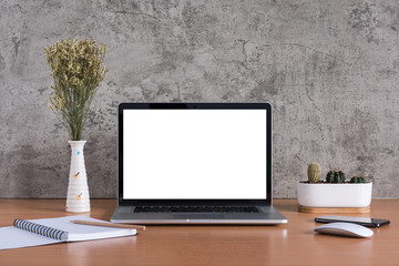 Blank screen of laptop computer with note book, pencil, dry flowers, Smart phone and cactus vase on raw concrete background