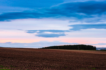 sunset landscape with rolling hills and woodland blue grey sky and orange sunset