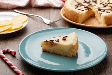 Homemade cheesecake sprinkled with chocolate chips on a blue plate. Wooden background, side view