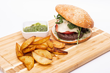 Fast food. Tasty burger with potato fries on a wooden board.
