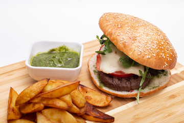 Fast food. Tasty burger with potato fries on a wooden board.

