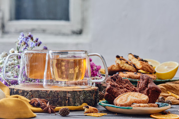 two glass cups of tea on a wooden saw, with cookies and dried flowers on the background. wooden background. autumn tea composition. close-up