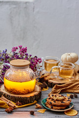 Transparent teapot, cookies with cranberries and two transparent cups of tea on wooden cuts and dried flowers on the background. Tea composition on wooden background. close-up. space