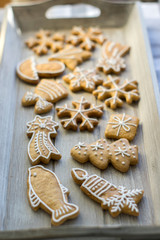 Painted traditional Christmas gingerbreads arranged on wooden tray in daylight, snowflakes and other Xmas symbols