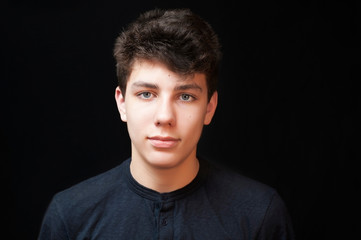 Obraz premium Portrait of a handsome teenage boy on a black background. The boy has dark hair and beautiful eyes