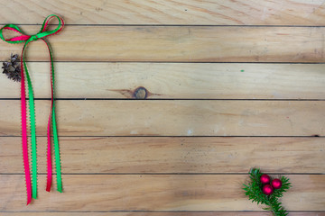 A green and red ribbon bow with cedar cones and red berries and  on greenery with copy space
